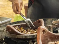 Preparing a dish in a clay pan at a live cooking station