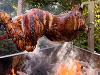 Roast lamb cooking over glowing coals