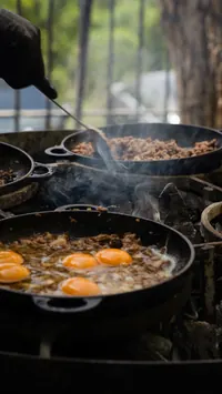 Eggs and meat sizzling in pans over the fire